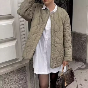 Detail der olivgrünen Steppjacke mit Druckknöpfen und lässigem Rundhalsausschnitt