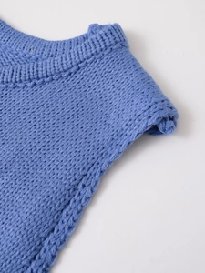 Close-up detail of blue chunky knit fabric showing ribbed neckline and texture