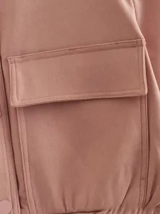Detail of the oversized flap pocket with double-stitching on a dusty pink bomber jacket