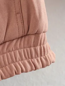 Detail of pink-brown bomber jacket featuring elastic ribbed cuffs and multi-row stitching