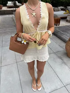 Close-up of sleeveless V-neck top with lace trim and white crochet hollow skirt