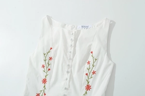 Detailed view of white square neck dress with floral embroidery and button closure