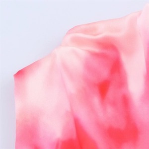 Macro shot of pink tie-dye satin fabric showing luxury silk texture and diagonal weave pattern