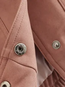 Detailed close-up of pink twill cotton jacket fabric with silver metal snap buttons