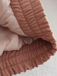 Close-up of pink quilted bomber jacket sleeve with elastic cuff and premium stitching