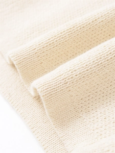 Gros plan sur la texture du tissu en maille côtelée blanc crème pour gilet de printemps
