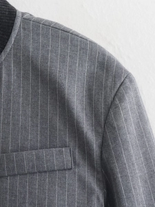 Close-up of dark grey pinstripe jacket featuring black ribbed collar and tape detail