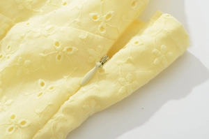Vista macro dettagliata del tessuto giallo ricamato a traforo con cerniera invisibile abbinata