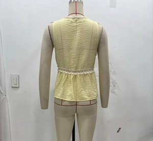 Detail of light yellow sleeveless top featuring white lace trim and peplum waist design