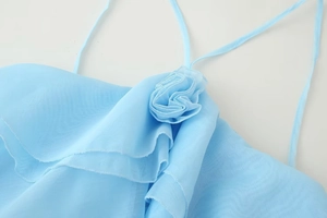 Macro detail of the 3D fabric flower and sheer textured fabric on light blue dress