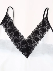 Close-up of white satin camisole top with black floral lace trim and V-neckline detail