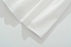 Detailed view of the clean stitched hem on a white cotton embroidered sleeveless dress
