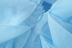 Detail of invisible zipper and sheer light blue mesh fabric on backless dress