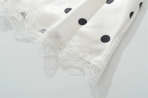 Detaillierte Makroansicht vom weißen Satinkleid-Saum mit Polka Dots und Spitzenbesatz