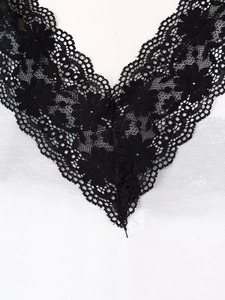 Detailed view of white fabric featuring intricate black floral crochet lace V-neckline