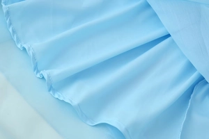 Detail shot of light blue chiffon dress featuring layered ruffles and delicate pleats