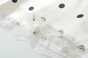 Detail aus weißem Polka-Dot-Satin mit eleganter Spitze am Saum des Damenkleides