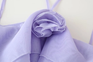 Detail of the light purple dress featuring a handcrafted 3D organza flower and thin straps
