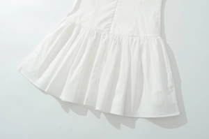 Close-up of white cotton dress hem featuring ruffled tiered layers and pleated texture