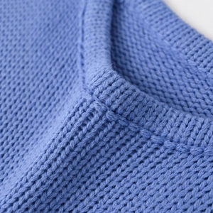 Close-up of blue one-shoulder asymmetric knit top featuring soft ribbed neckline texture