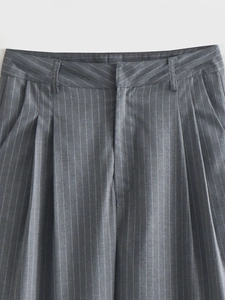 Detail of waist pleats and belt loops on dark gray striped trousers for women