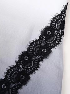 Detailed close-up of delicate black floral lace stitching on smooth grey satin fabric