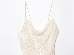 Detail of white sequined slip dress featuring a cowl neck and shimmer finish