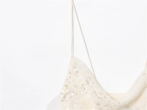 Detail of white sequined summer dress with thin spaghetti straps and sparkling texture