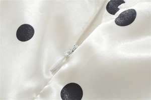 Nahaufnahme von weißem Satin mit schwarzen Punkten und hochwertigem verdecktem Reißverschluss