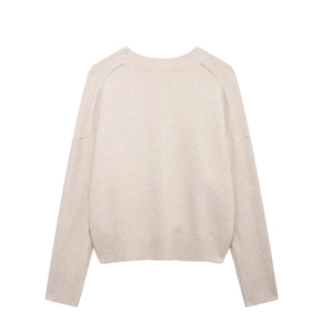 Close-up of beige knit sweater showing ribbed crew neck and soft wool texture