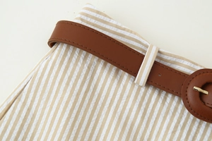 Détail d'un short en lin rayé avec ceinture en similicuir marron et boucle dorée