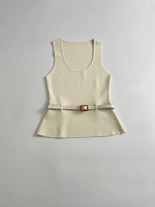 Close-up of cream knit sleeveless top featuring a peplum hem and buckled waist belt