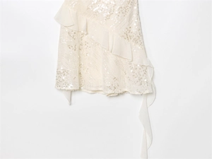 Macro detail of white sequined fabric with pleated ruffle trim on a party dress