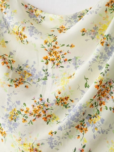 Detail of satin floral fabric with yellow and purple flowers on an off-white background