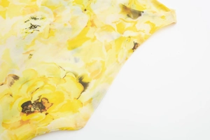 Close-up of yellow floral print mesh fabric with delicate summer garden pattern detail
