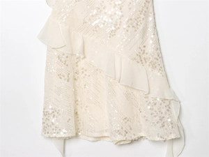 Detailed view of cream sequin embroidery and layered chiffon ruffles on a mini dress