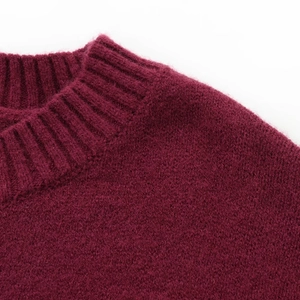 Detail of the crew neck and ribbed texture on this burgundy wool knit sweater