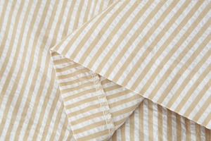 Gros plan d'un tissu rayé beige en coton et lin avec surjet blanc détaillé de qualité