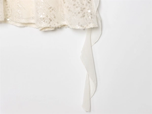 Detailed view of cream mesh dress featuring shimmering sequins and tiered ruffle edges