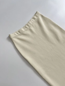 Detail shot of a minimalist cream knitted skirt showing elastic waistband and fine texture