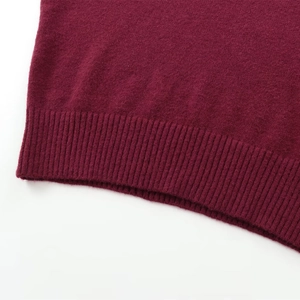 Close-up of ribbed hem on burgundy knit sweater with soft wool texture and fine stitching