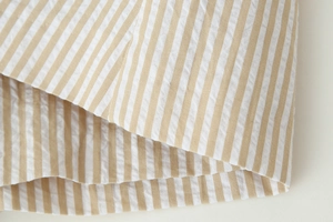 Détail du tissu seersucker à rayures verticales jaune clair et blanc avec coutures fines