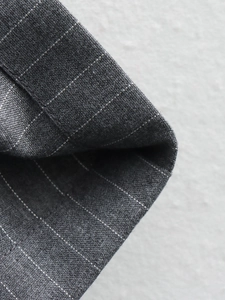 Close-up of premium dark grey fabric with fine pinstripes and high-quality texture