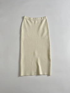 Detailed close-up of beige knitted midi skirt showing elastic high waist and fine fabric texture