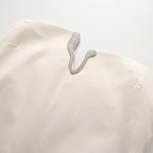 Gros plan du décolleté de la robe ivoire avec un accent métallique en forme de serpent orné de strass