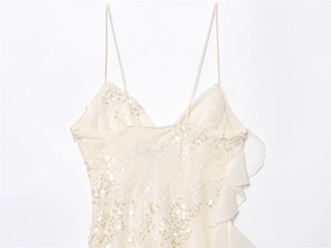 Detailed macro view of white sequin embroidery and layered ruffle design on party dress
