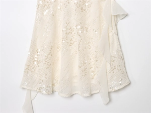 Detail of sequins and chiffon ruffle hem on an elegant ivory tiered party dress