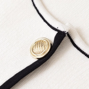 Veste en maille blanche avec bordure contrastée noire et bouton doré texturé chic