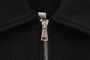 Macro shot of high-quality silver metal zipper on premium black wool jacket fabric
