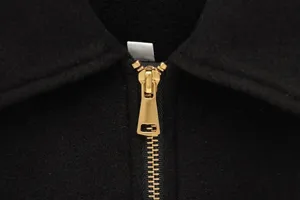 Macro shot of high-quality silver metal zipper on premium black wool jacket fabric